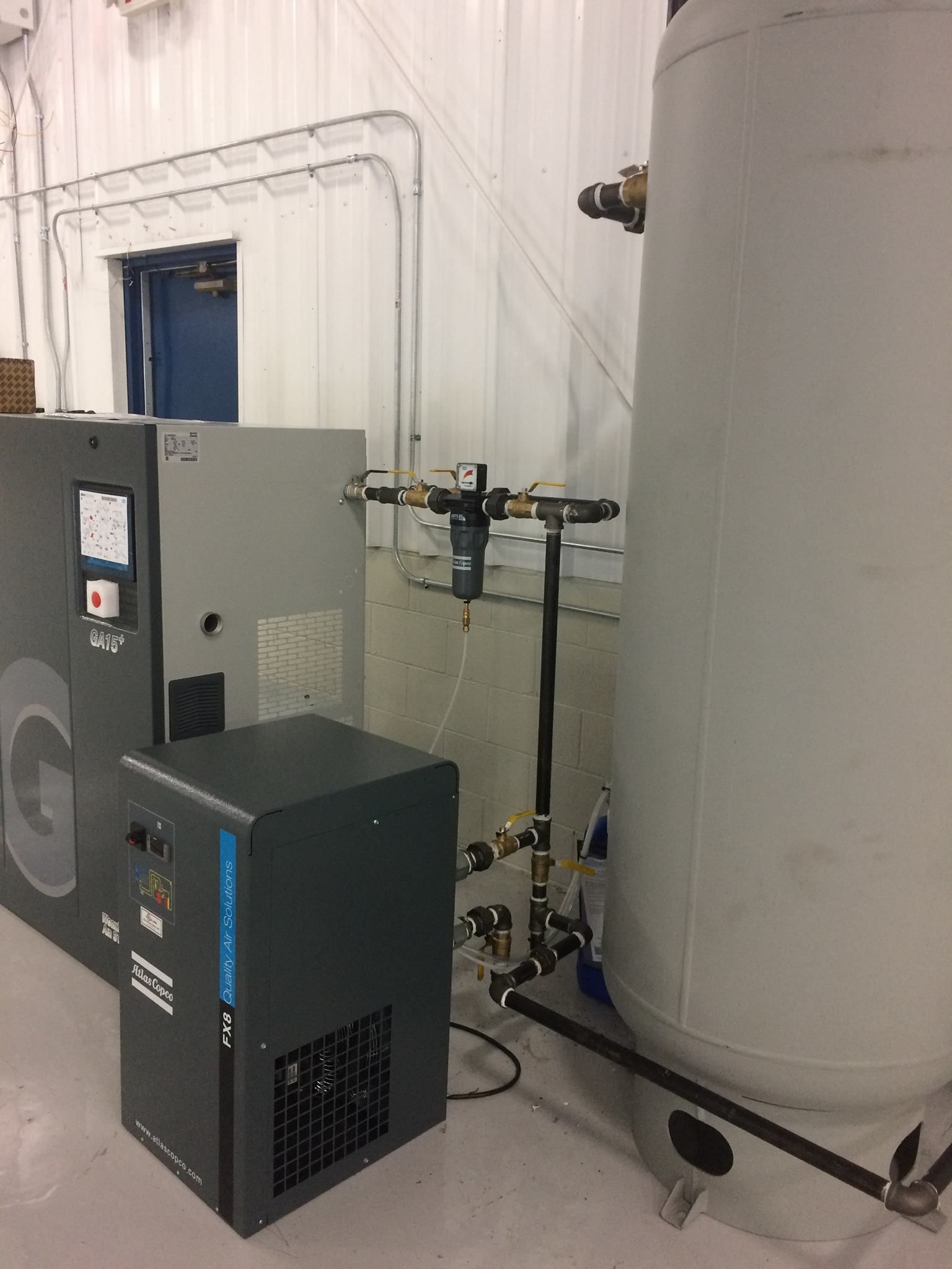 A machine is sitting next to a large tank in a room.