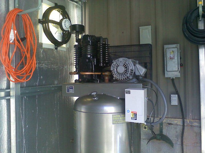 An air compressor is mounted to a wall in a garage