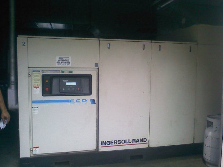 An ingersoll rand air compressor is sitting in a garage.