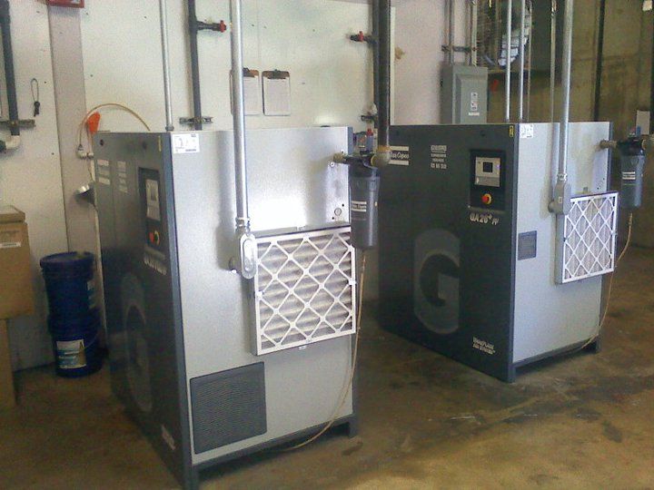Two air compressors are sitting next to each other in a room.