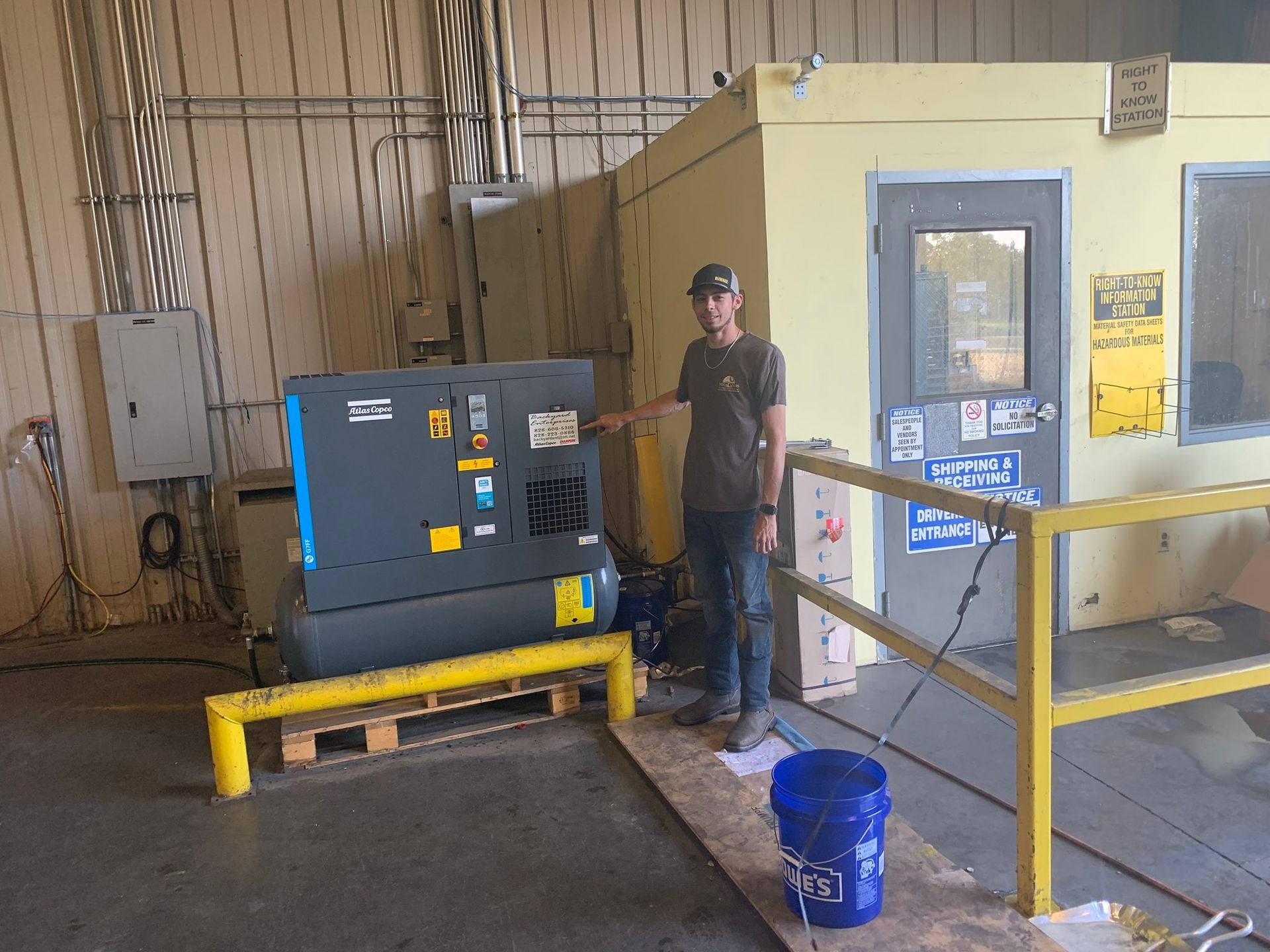 A man is standing in front of a machine in a warehouse.