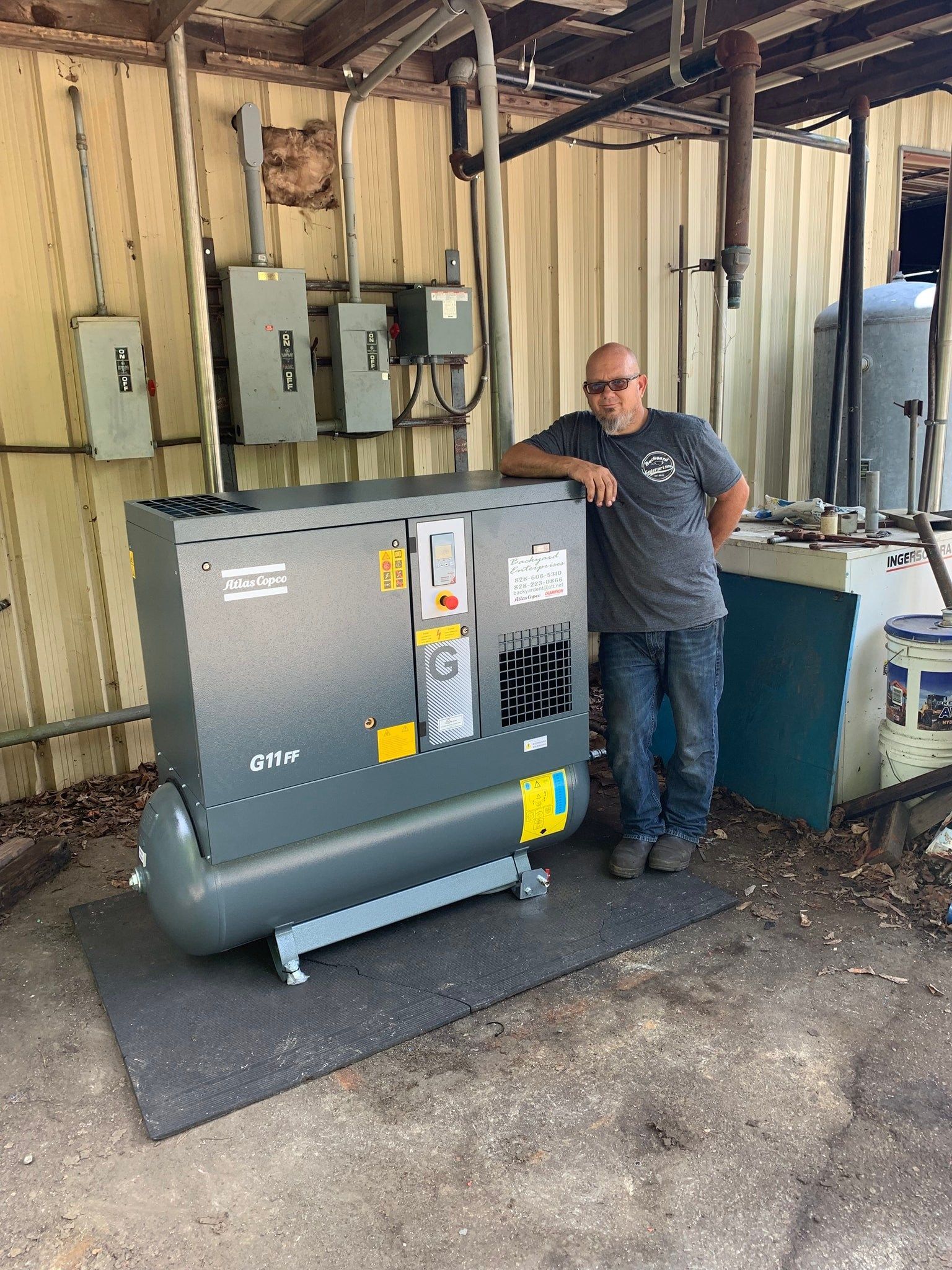 A man is standing next to a large air compressor.