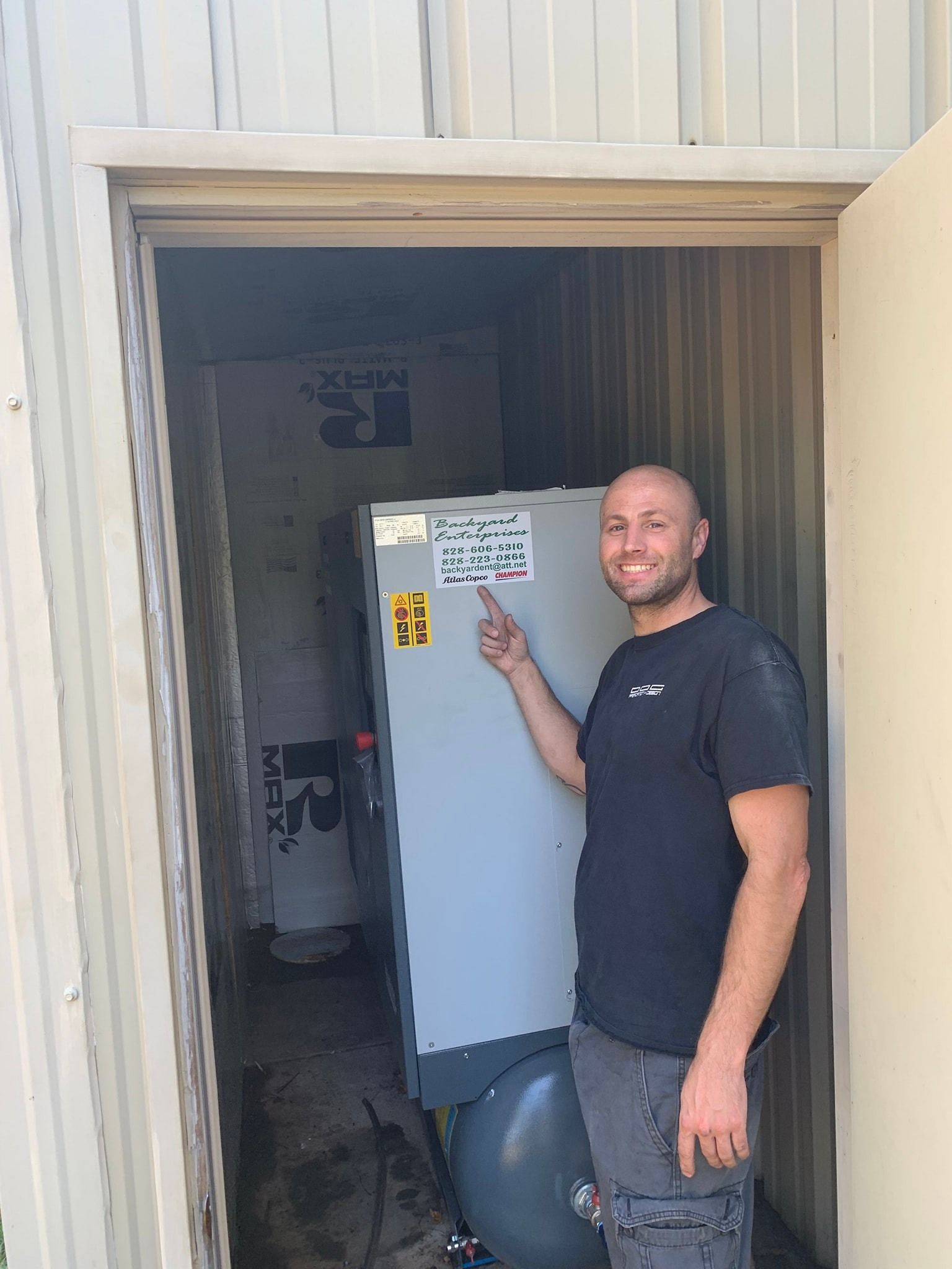 A man is standing in a doorway pointing at a refrigerator.