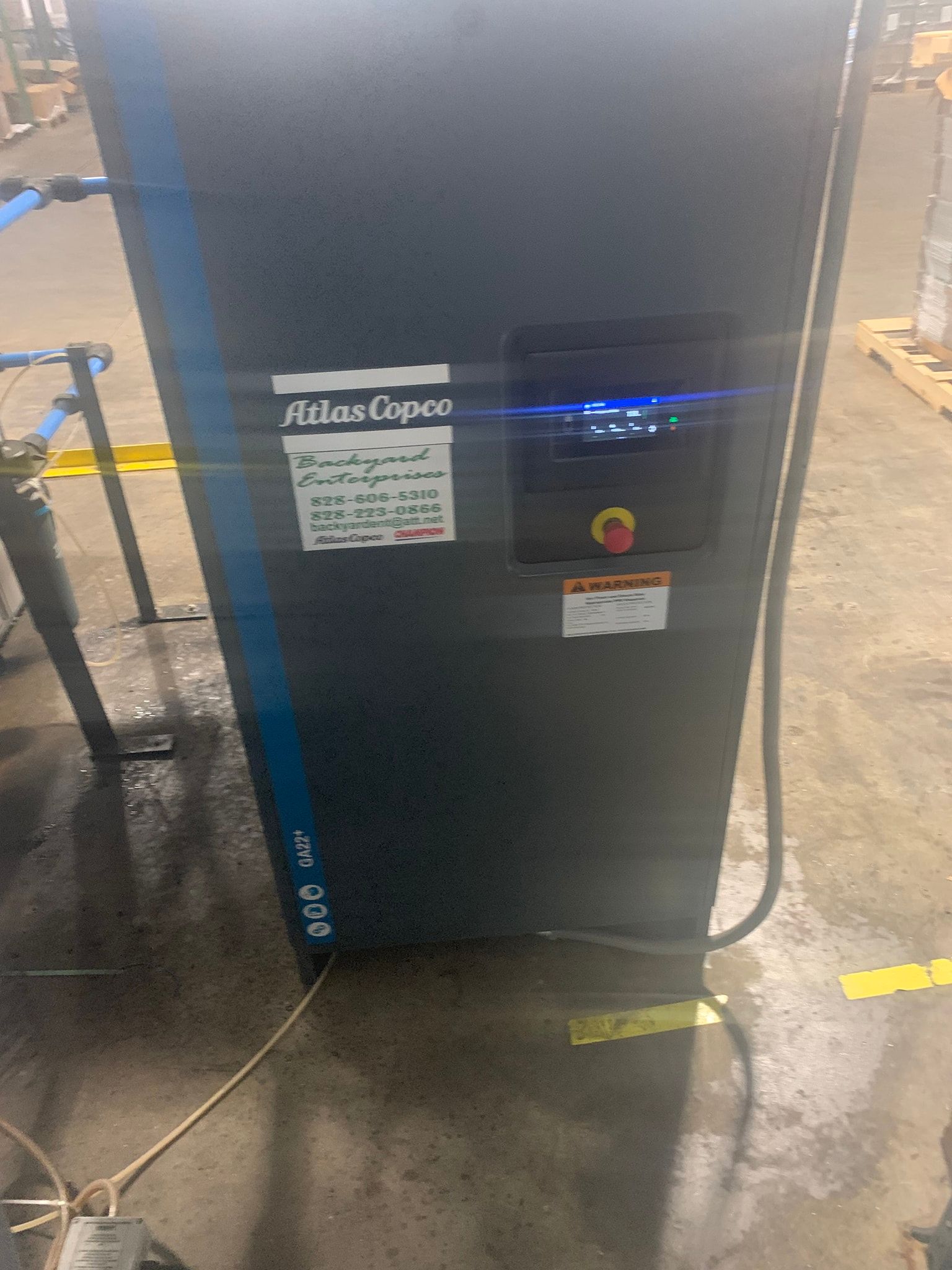 A black and blue air compressor is sitting on a concrete floor in a warehouse.
