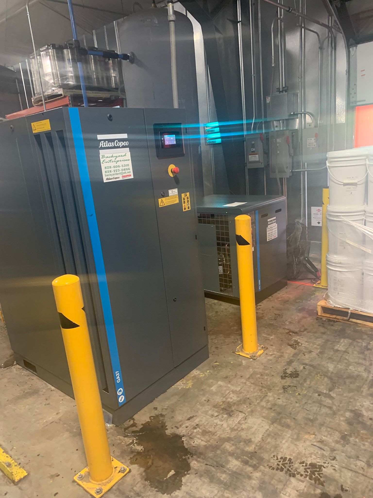 A large machine is sitting in a warehouse next to yellow poles.