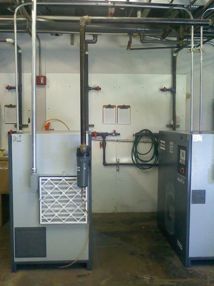 Two air compressors are sitting next to each other in a room