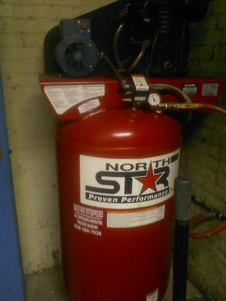A red north star air compressor is sitting on a wall.