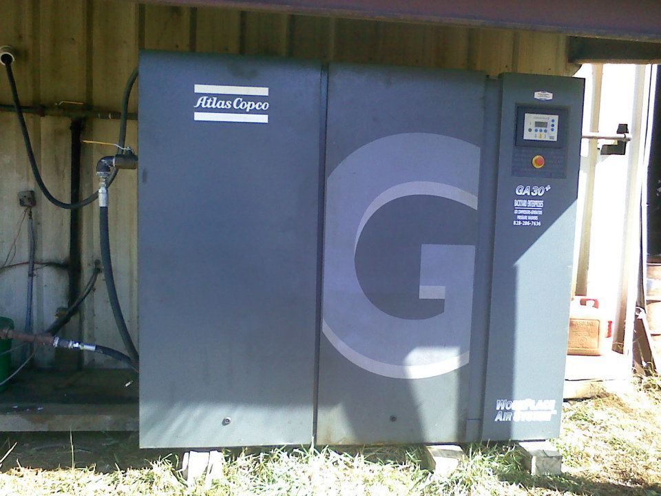 An atlas copco air compressor is sitting outside of a building