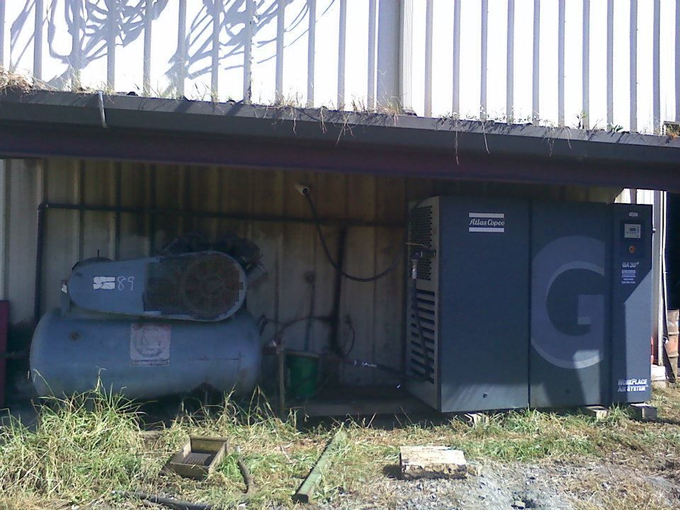A large air compressor is sitting under a building