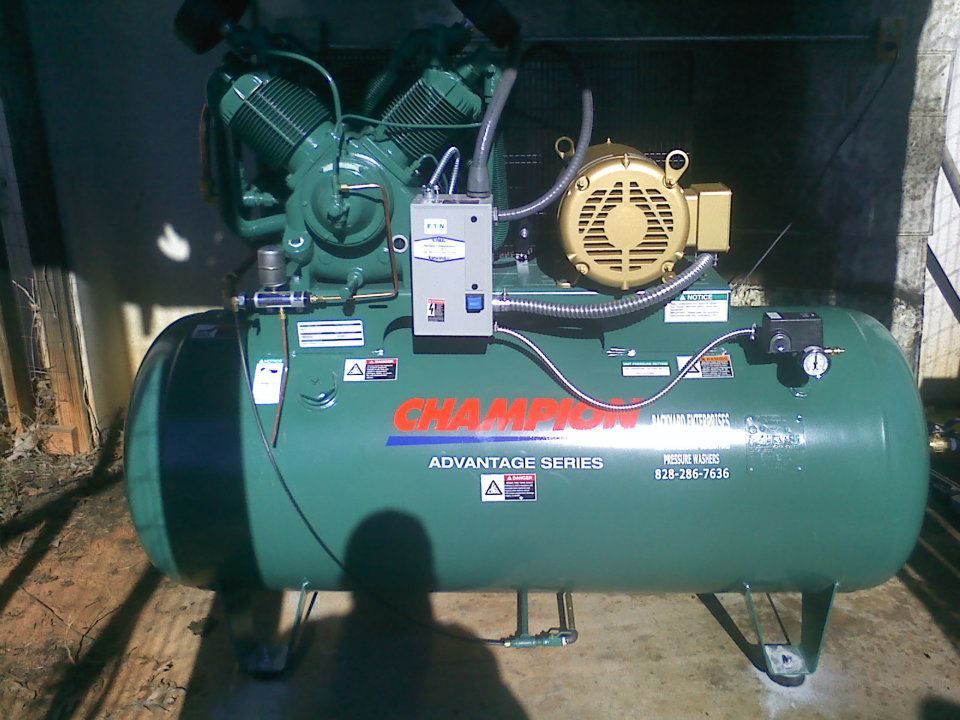 A green champion air compressor is sitting on the ground