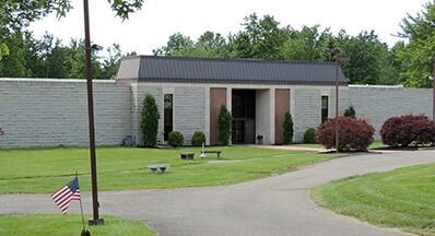 The front door of a house with a porch and plants in front of it.