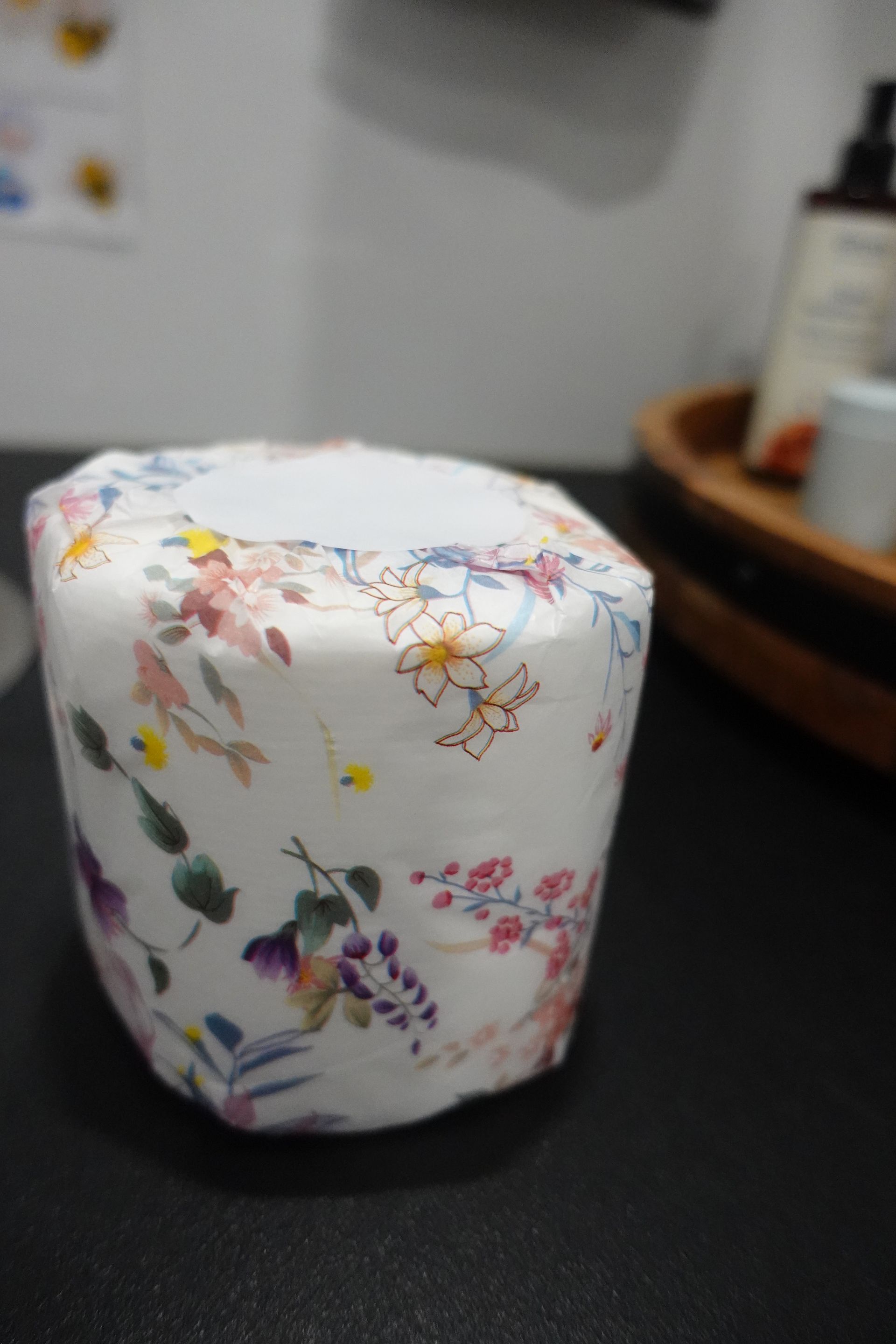 A roll of toilet paper with flowers on it is sitting on a table.