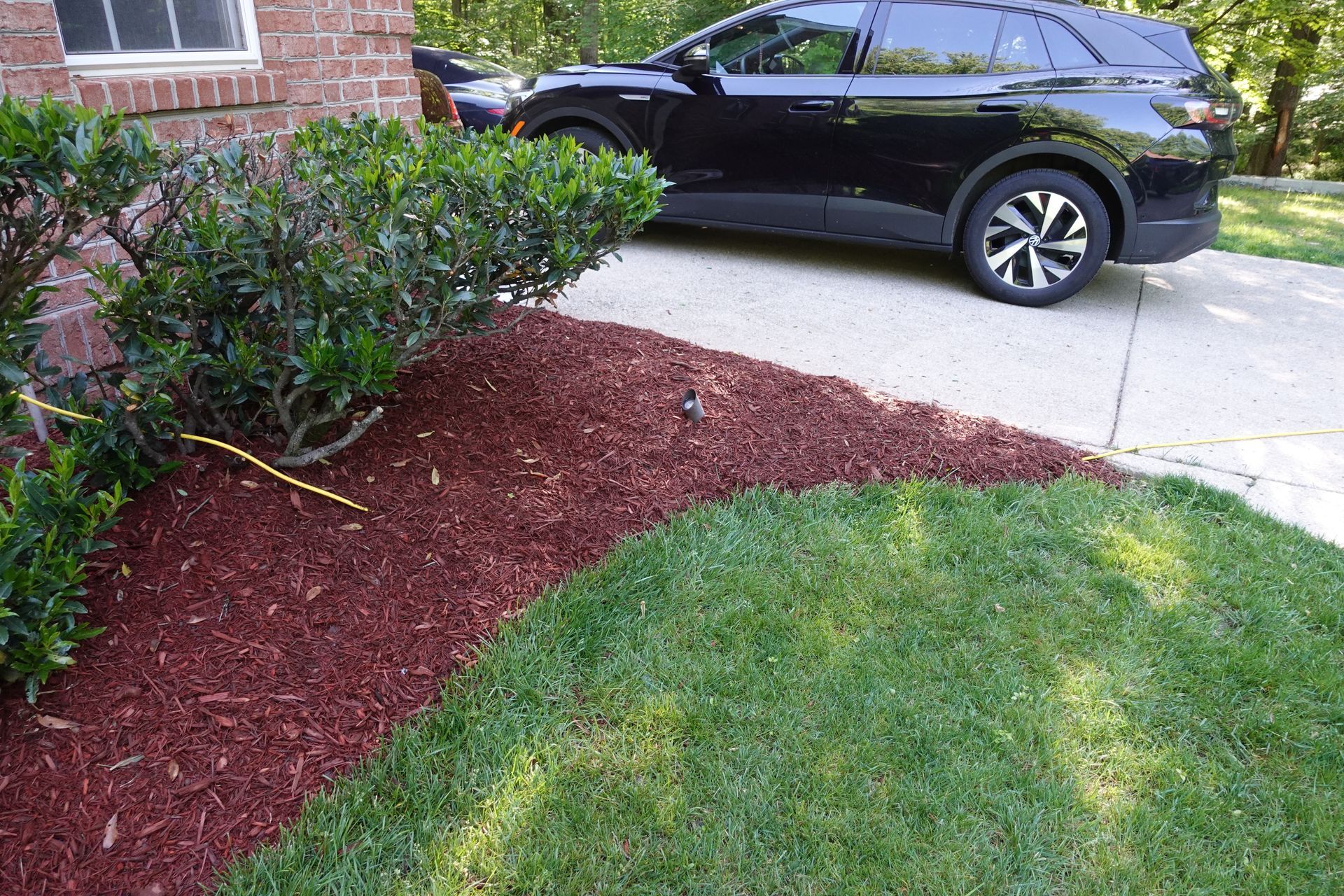 A black suv is parked in a driveway next to a pile of mulch.
