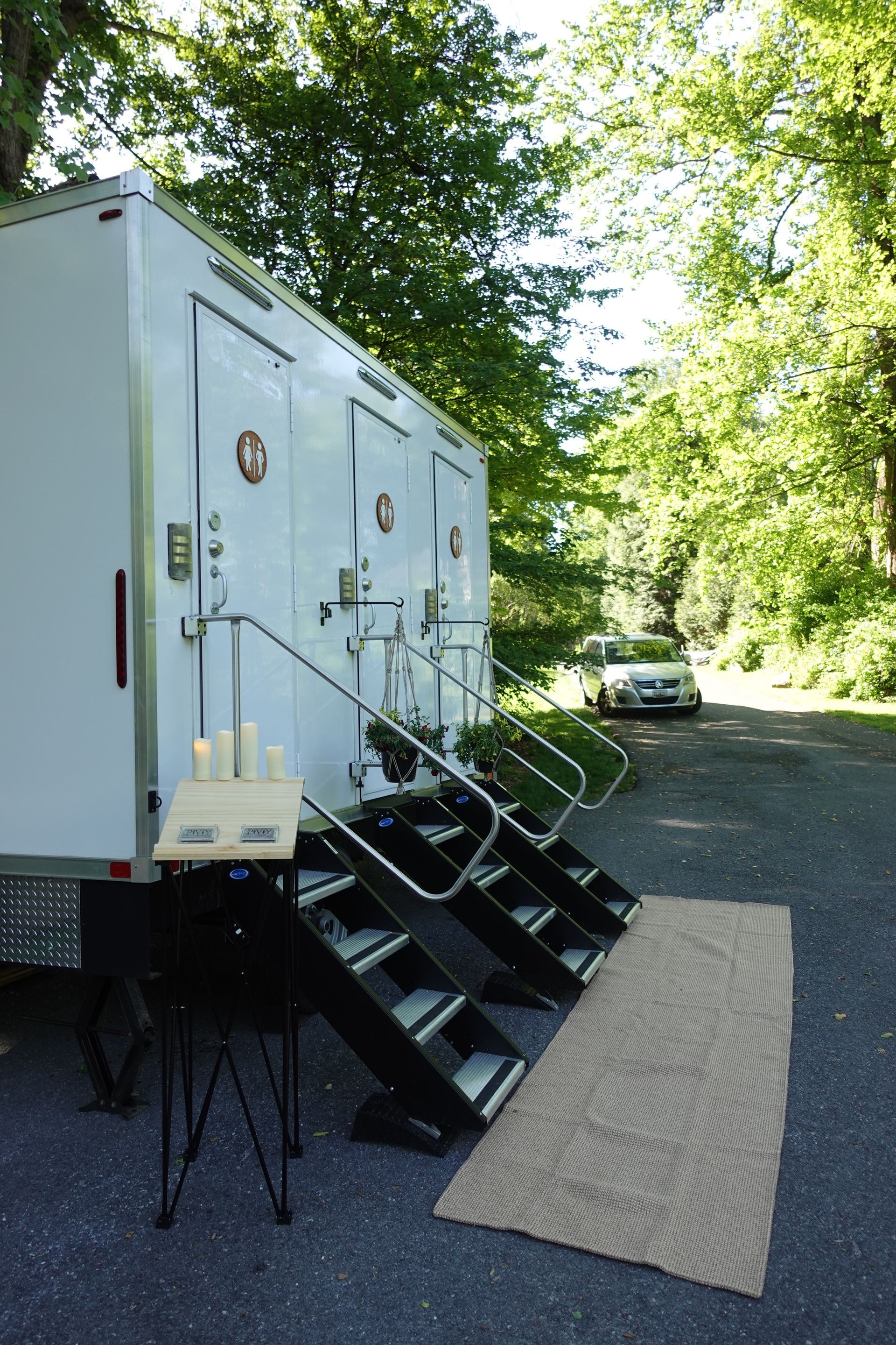 A white trailer with stairs leading up to it is parked on the side of the road.