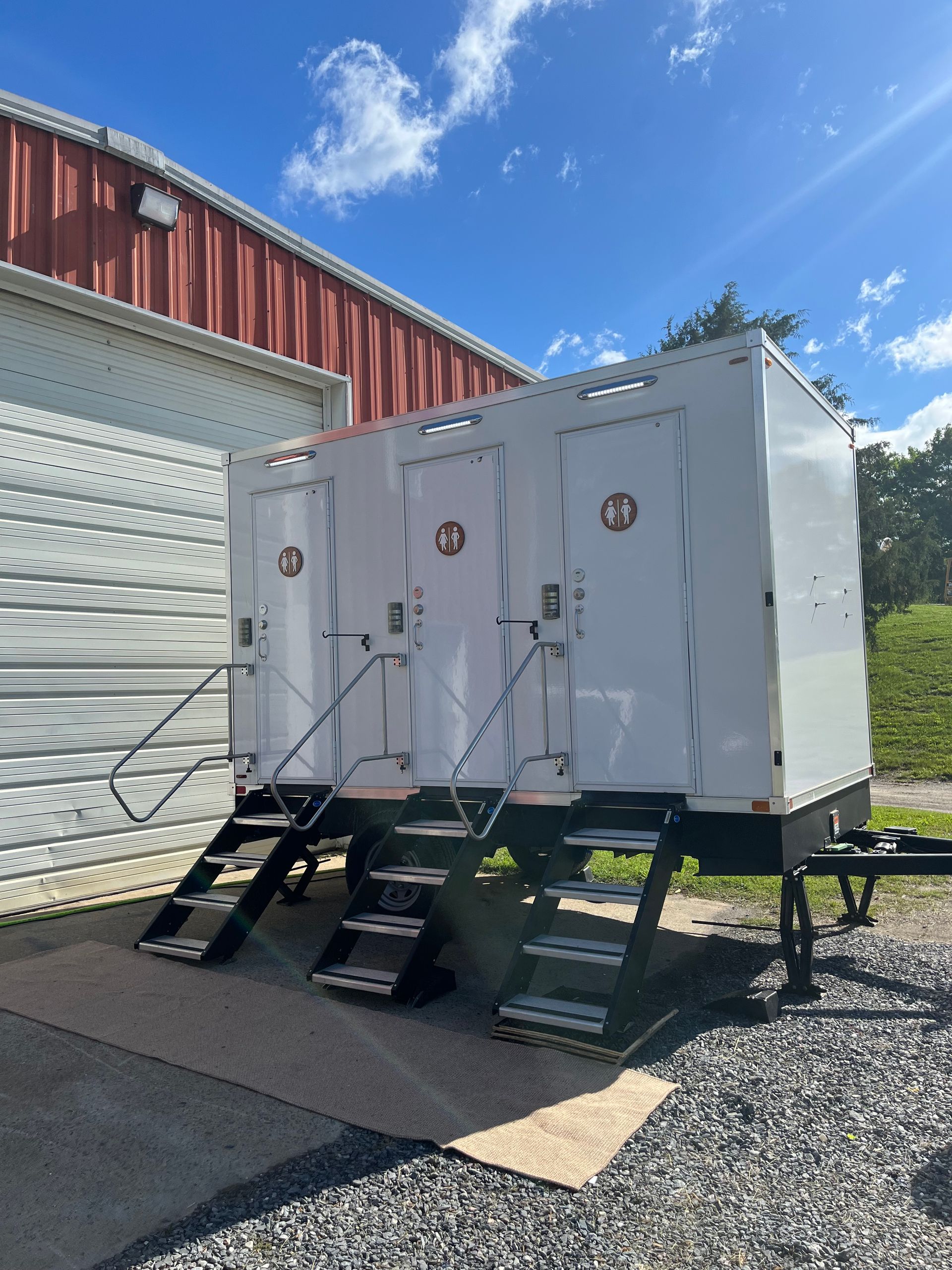 A trailer with three toilets on it is parked in front of a building.