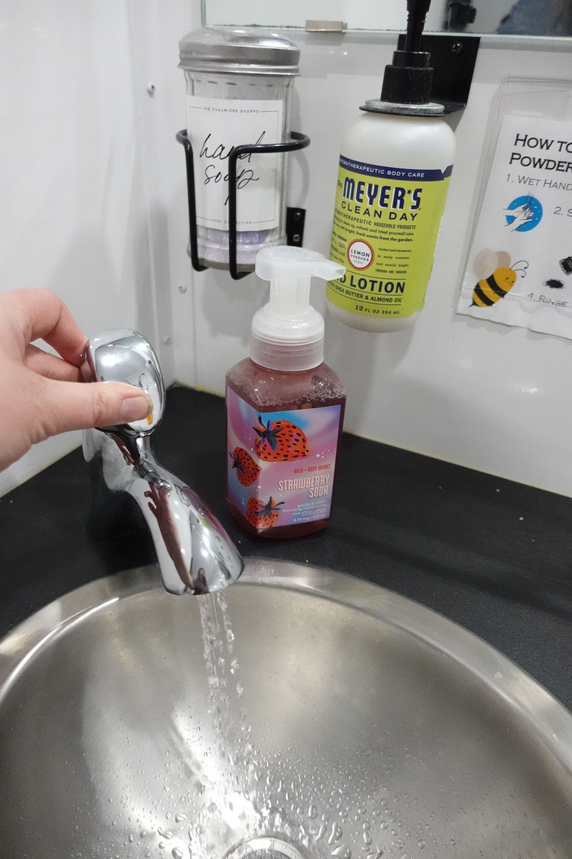 A person is washing their hands in a bathroom sink.