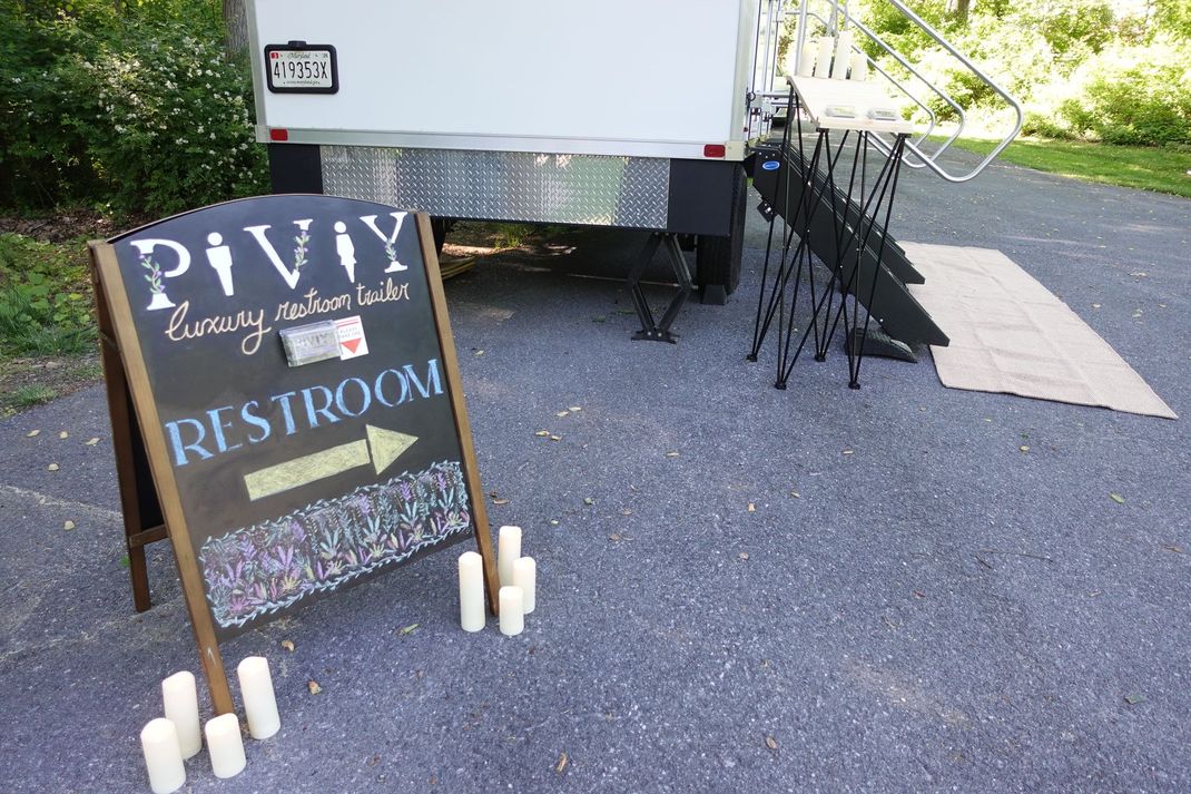 An aerial view of a portable restroom trailer on a lush green field.