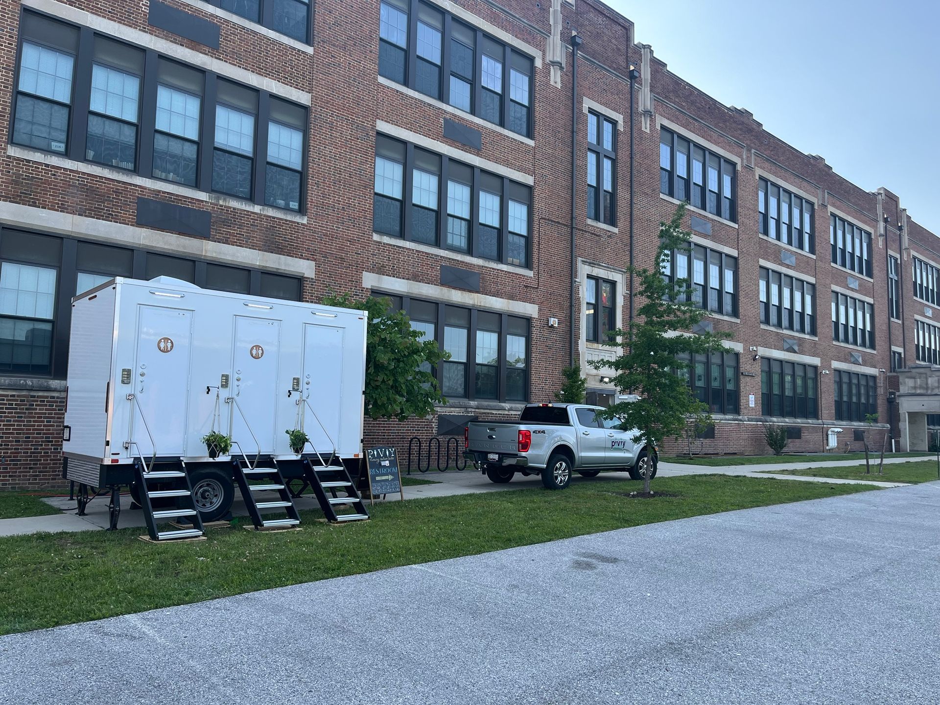 A white truck is parked in front of a large brick building.