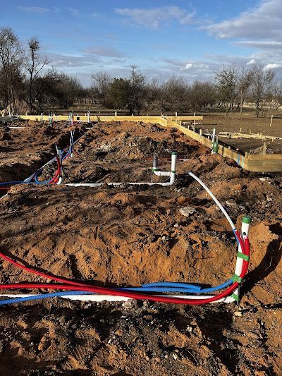A bunch of pipes are laying in the dirt on a construction site.