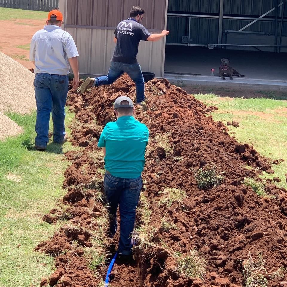 A man wearing a shirt that says ' aa ' on it is digging in the dirt