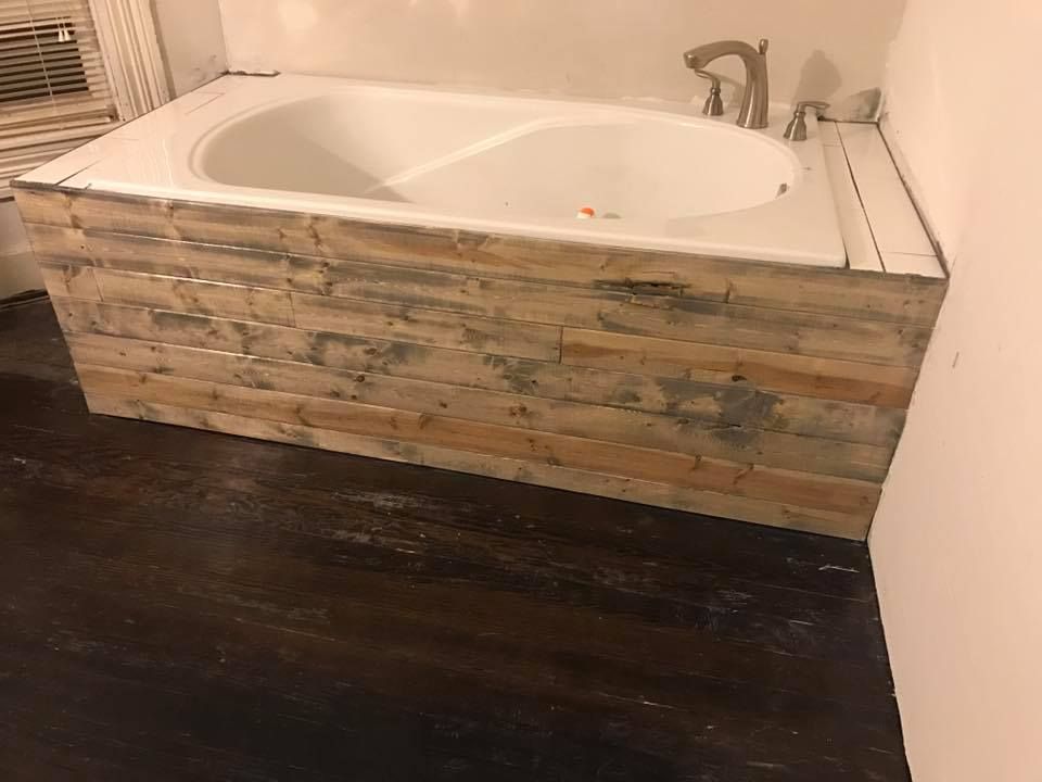 A bathtub is surrounded by wooden blocks in a bathroom.