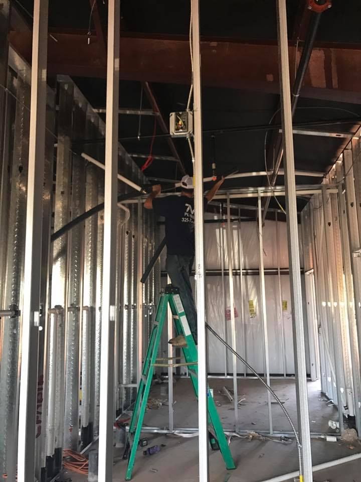 A man is standing on a ladder in a building under construction.