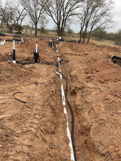 A bunch of pipes are laying in the dirt in a field.