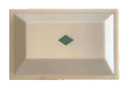 Cream-colored rectangular button with a green diamond in the center and angled edges.