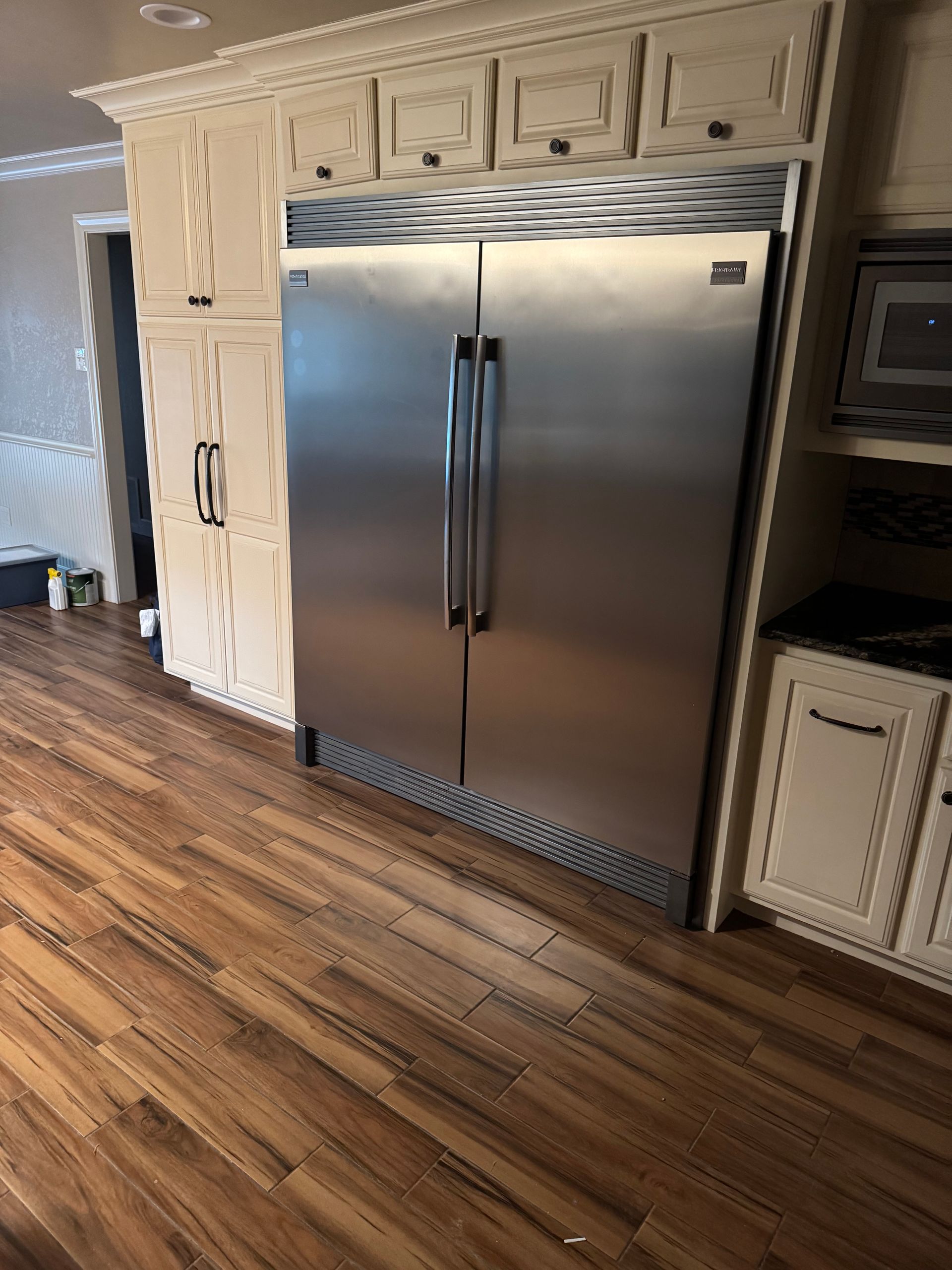 A stainless steel refrigerator is built into the wall of a kitchen.