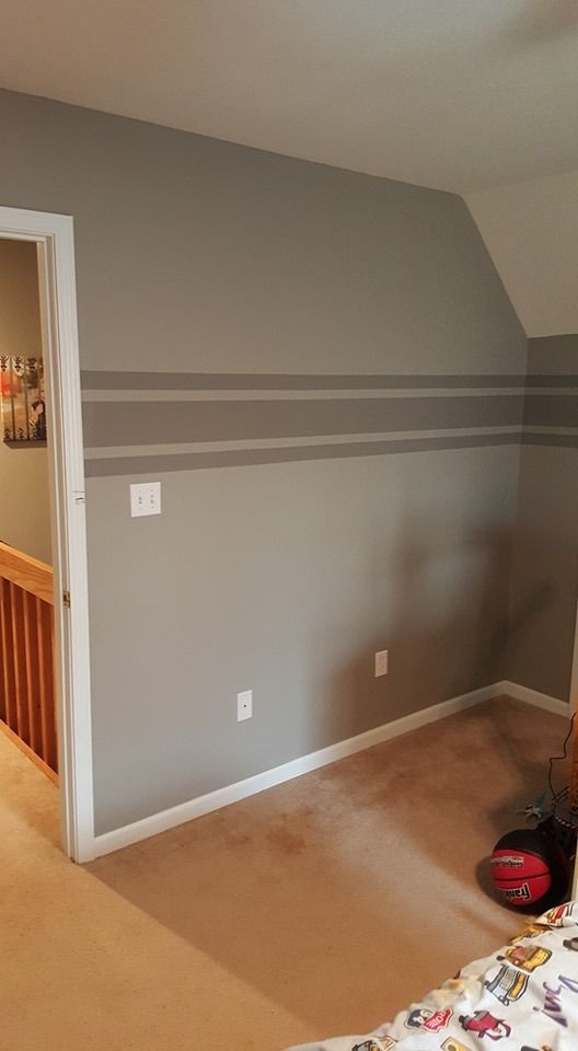 A room corner with light gray walls featuring two horizontal stripes of a darker gray shade.