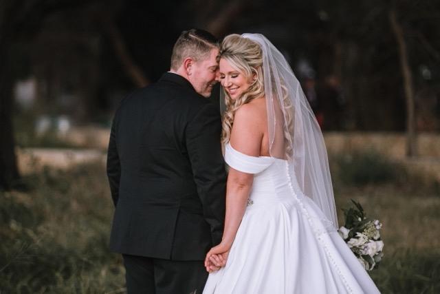 a bride and groom are posing for a picture in a field .