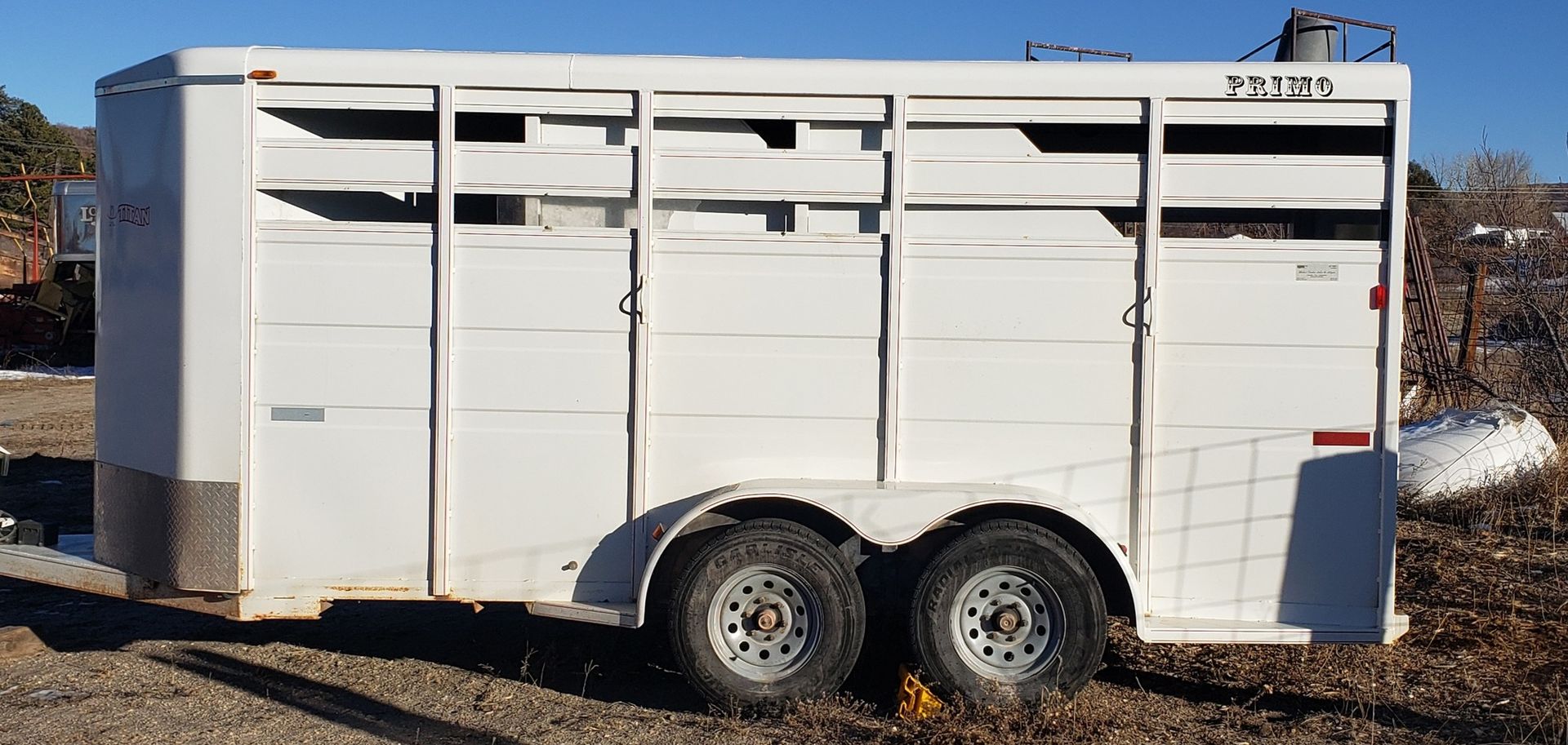a black horse trailer is parked in a field .