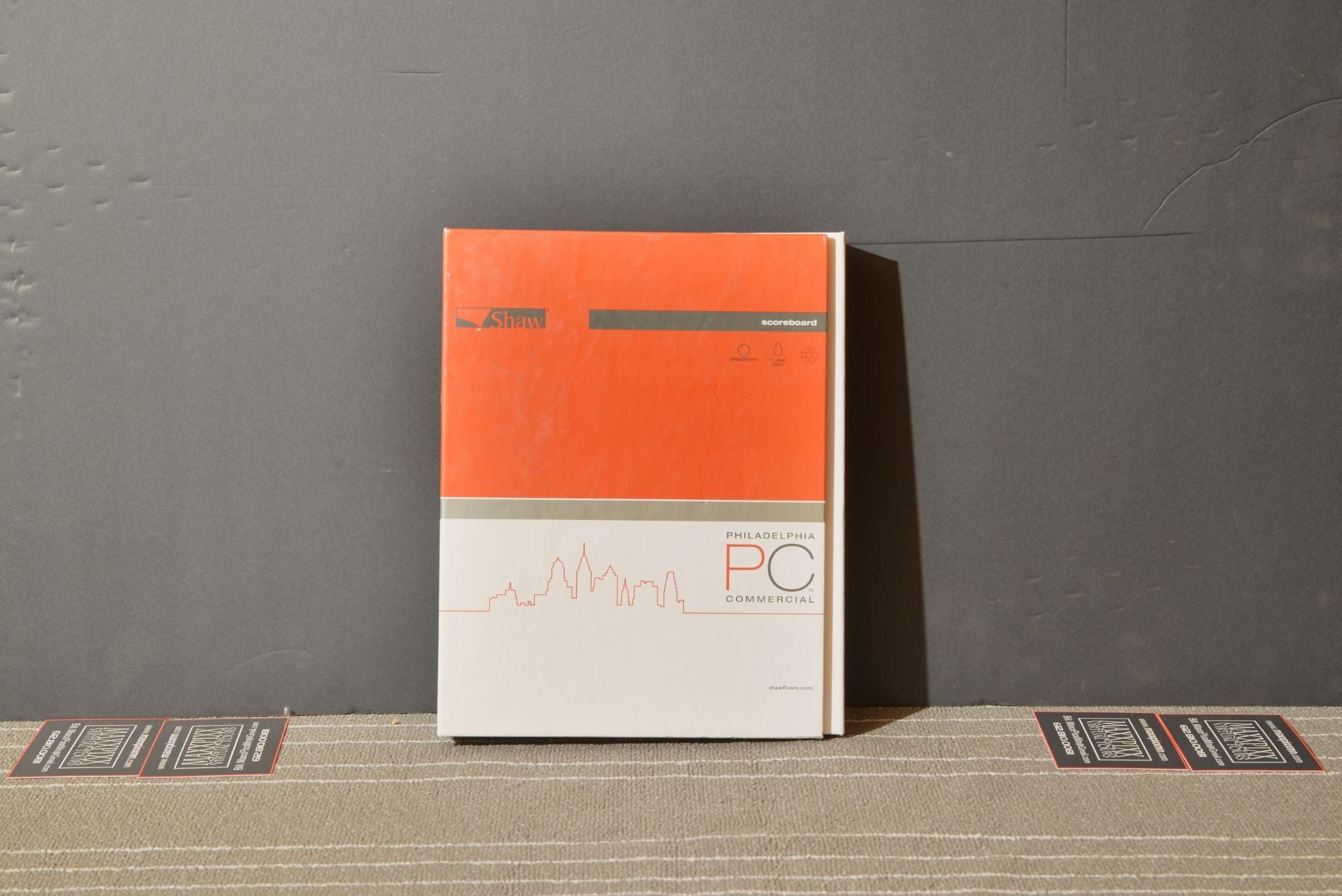 A book is sitting on a carpet next to a wall.