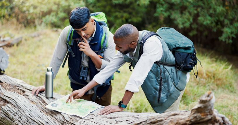Two hikers taking out a map to recalibrate their journey