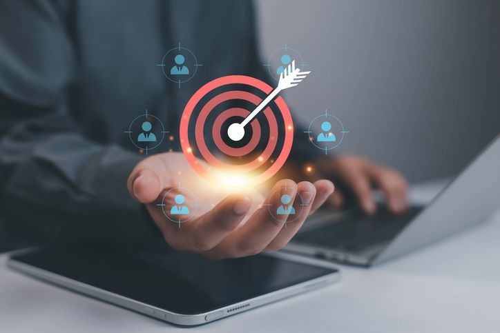 Businessman holding target with an arrow in the bullseye.