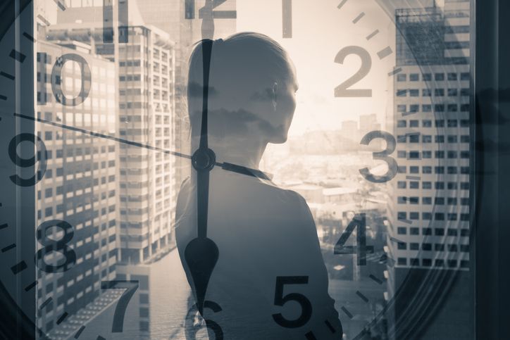 Businesswoman calmly looking out office window. Clock overlay.