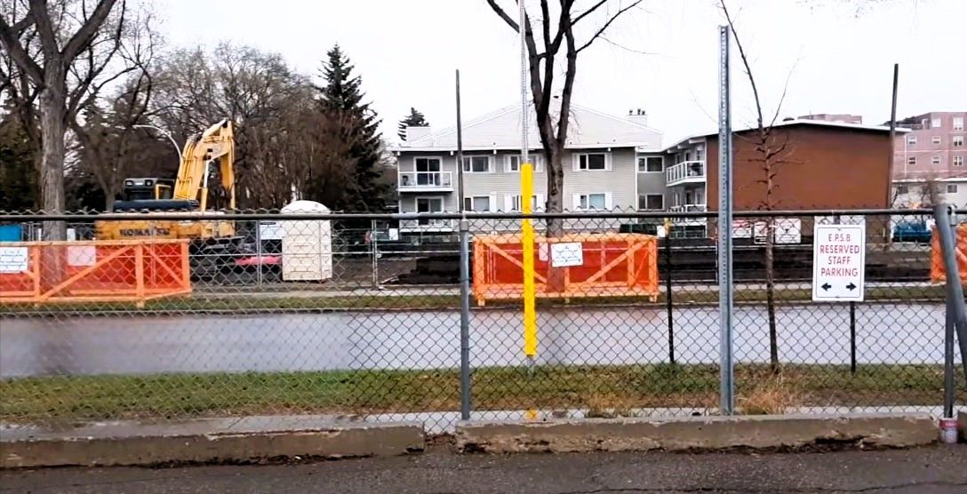 A construction site with orange fencing and equipment, ensuring the protection of a tree during construction.