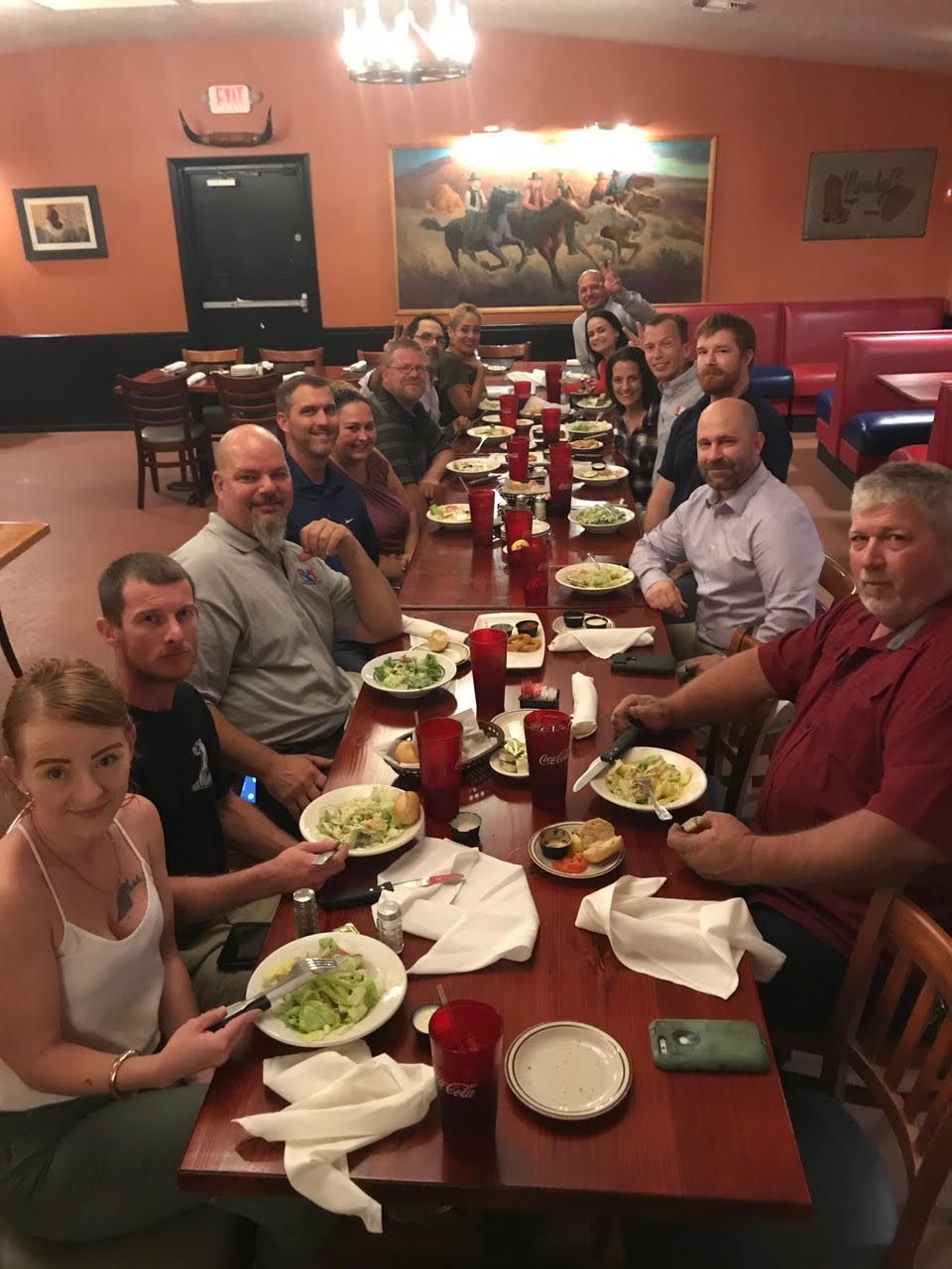 A group of people are sitting at a long table eating food