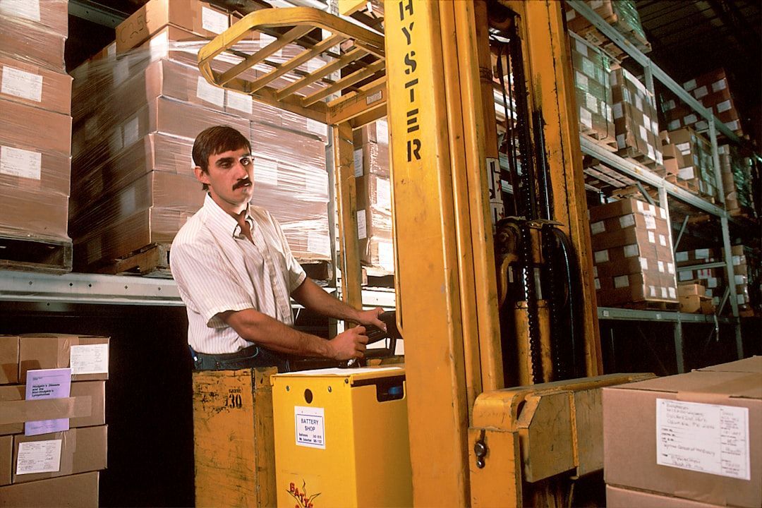 A man is driving a yellow hyster forklift in a warehouse
