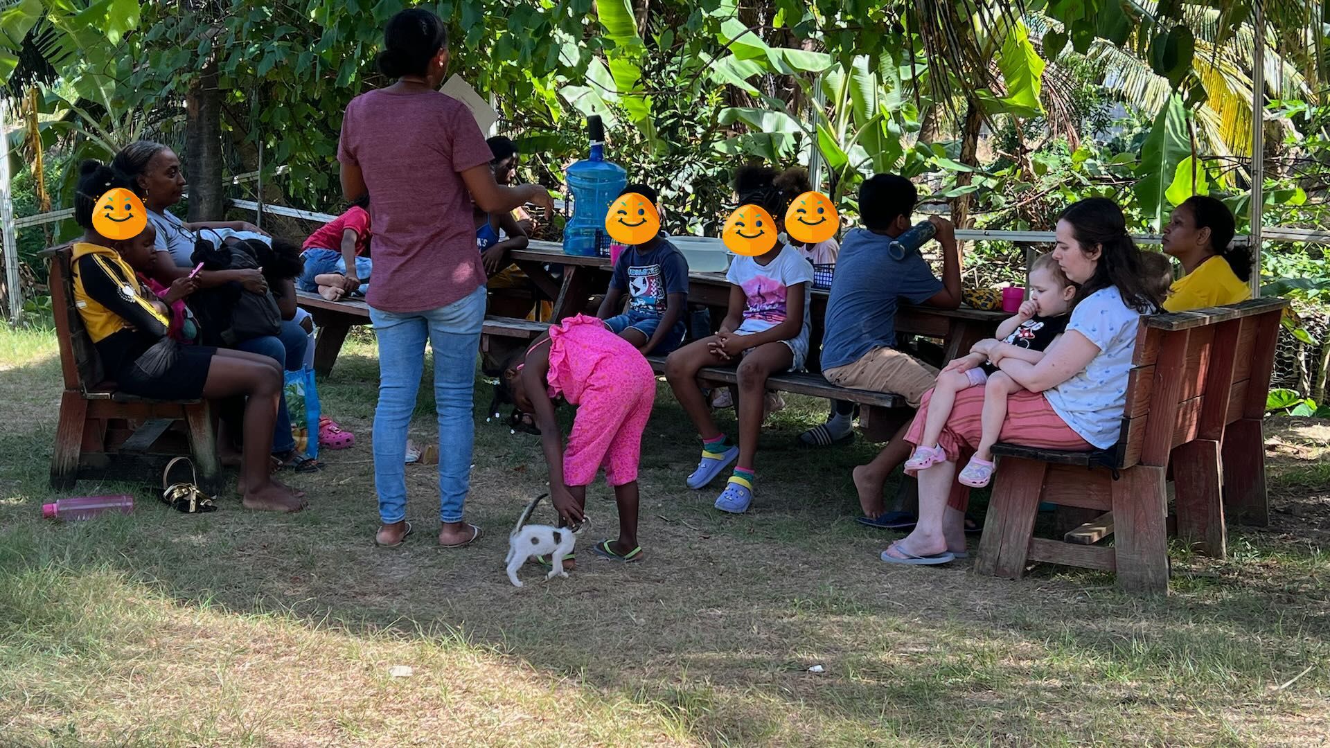 A group of people are sitting around a picnic table in a park.