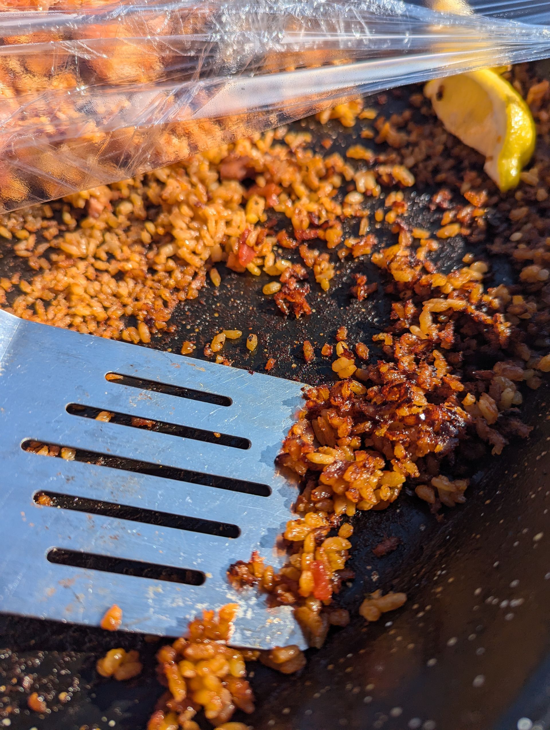 Paella pan with a spatula scraping crispy, browned rice.