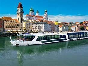 River cruise ship in Passau, Germany, with colorful buildings and towers in the background.