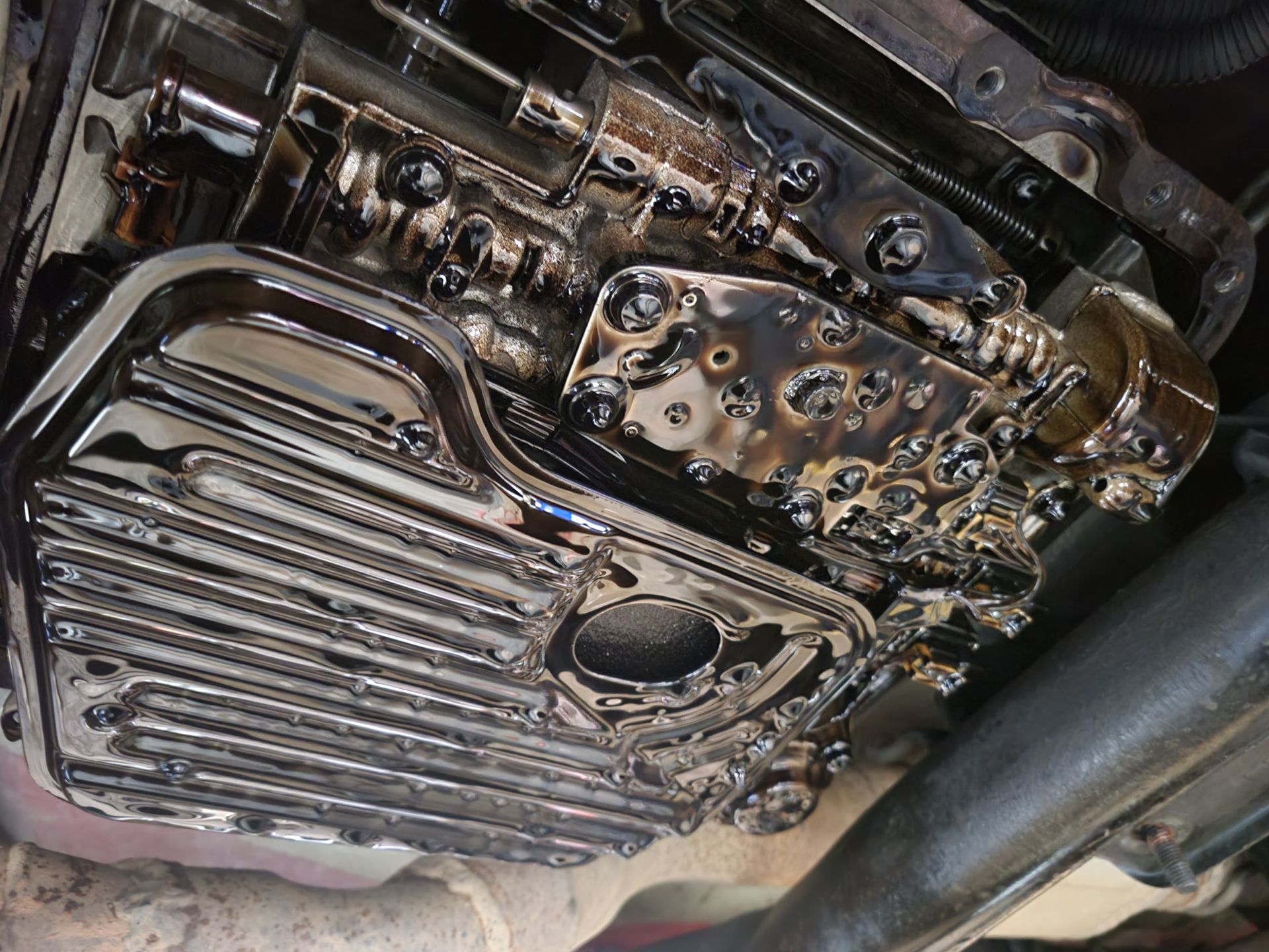 Transmission oil pan and valve body, coated in dark oil. | Countryside Automotive