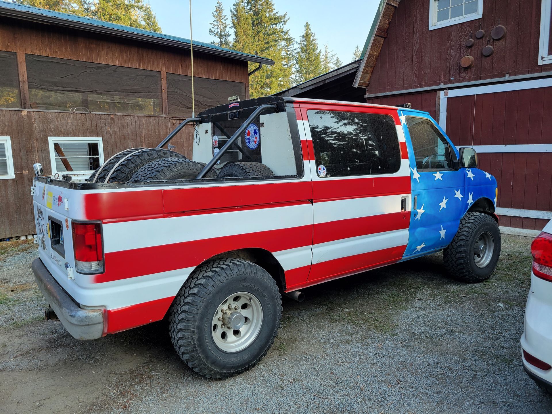 American flag-painted van with large tires parked outside a building. | Countryside Automotive