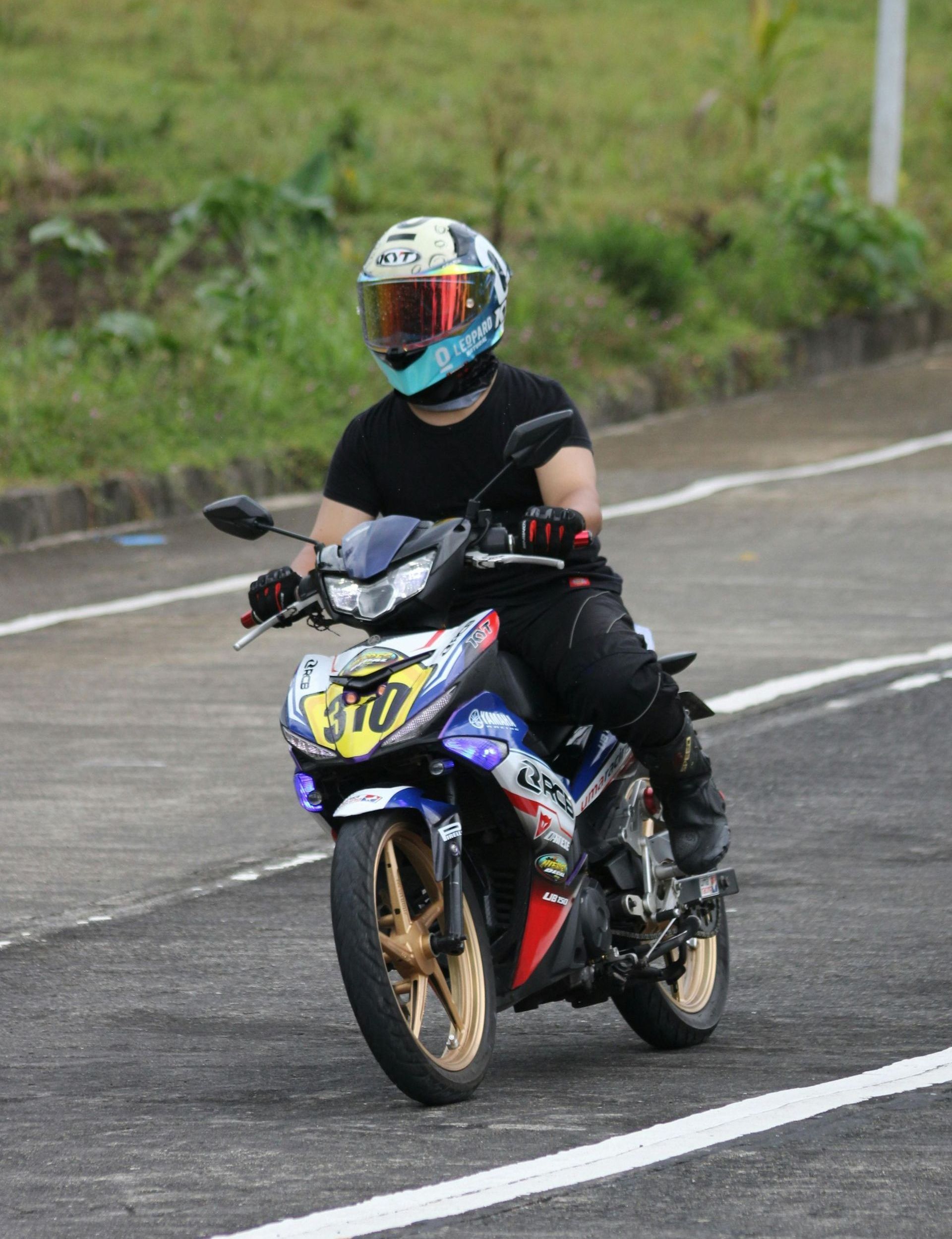 A man wearing a helmet is riding a motorcycle down a road.