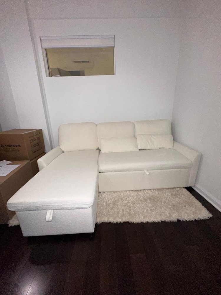 A white sectional couch is sitting in a living room next to a window.