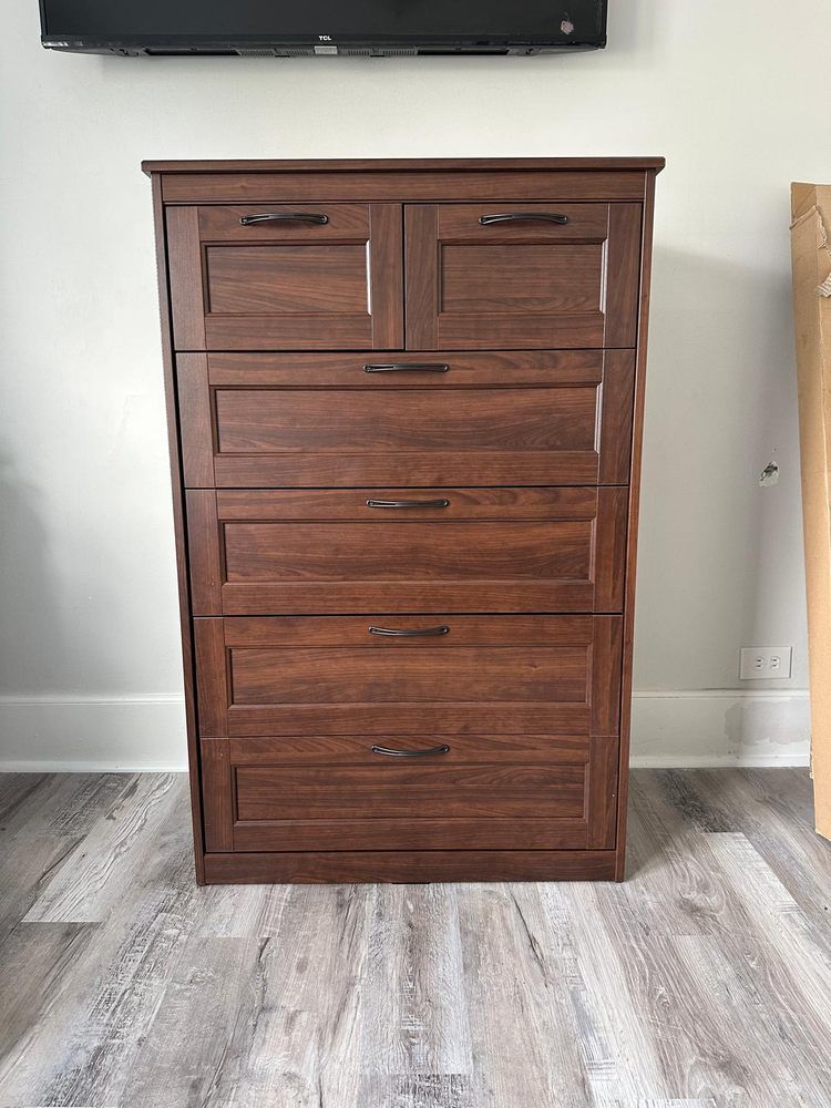 A wooden chest of drawers is sitting on a wooden floor in a living room.