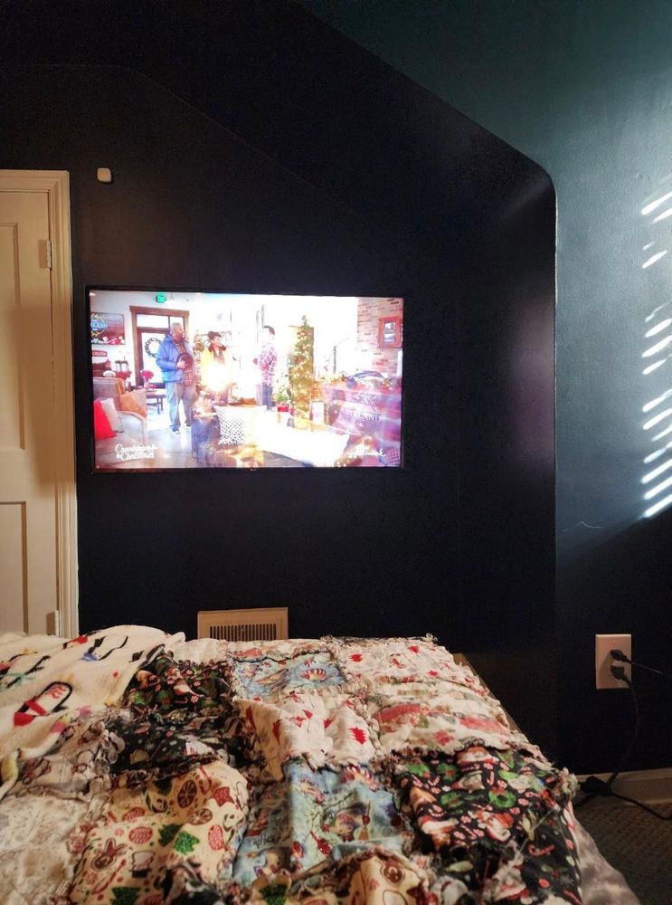 A bedroom with a bed and a television on the wall