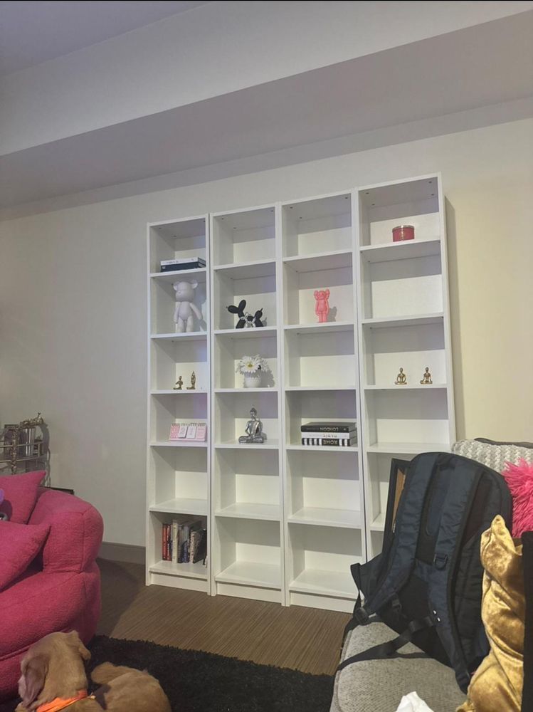 A living room with a lot of shelves and a pink couch