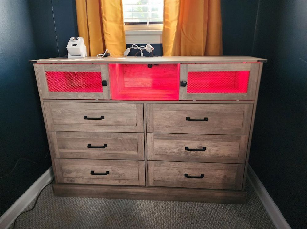 A dresser with red lights on the drawers in a room